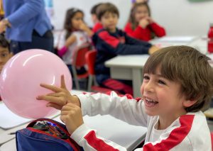 A smiling child with a pink balloon.